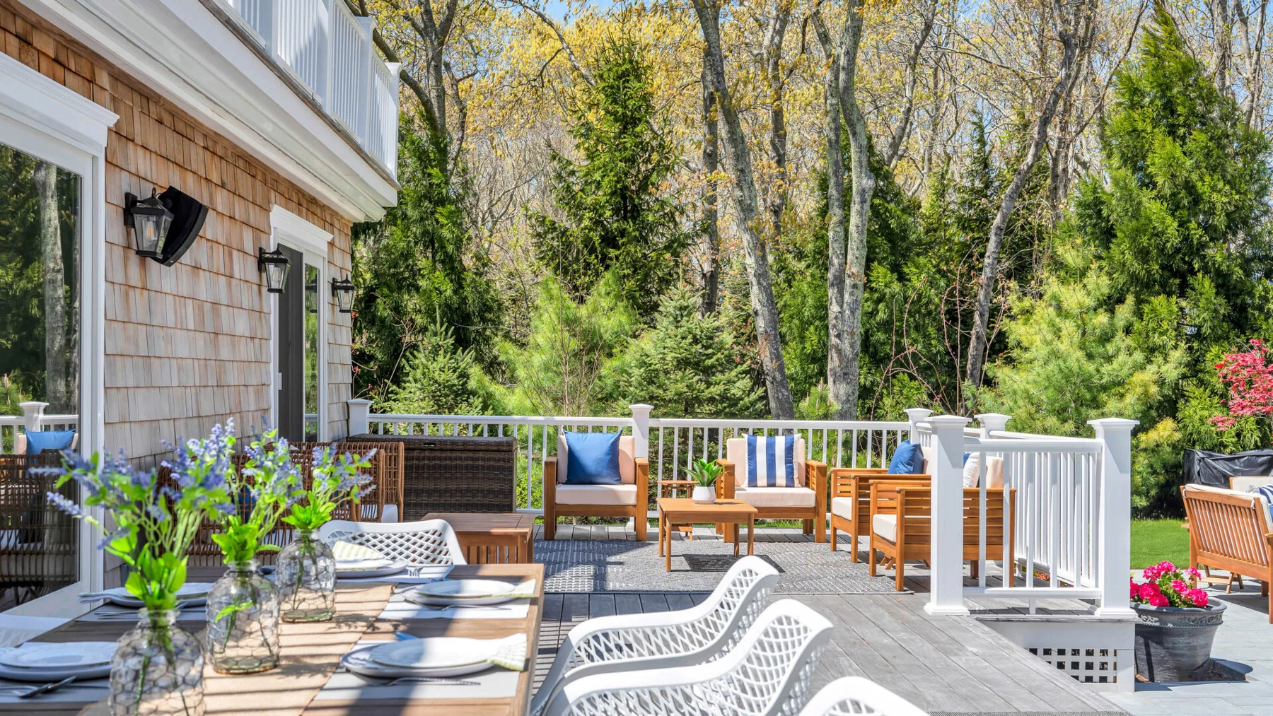 A wooden deck with outdoor seating overlooks a wooded garden.