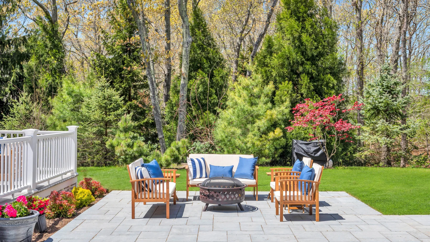 An outdoor patio seating area with a central fire pit and surrounding greenery.