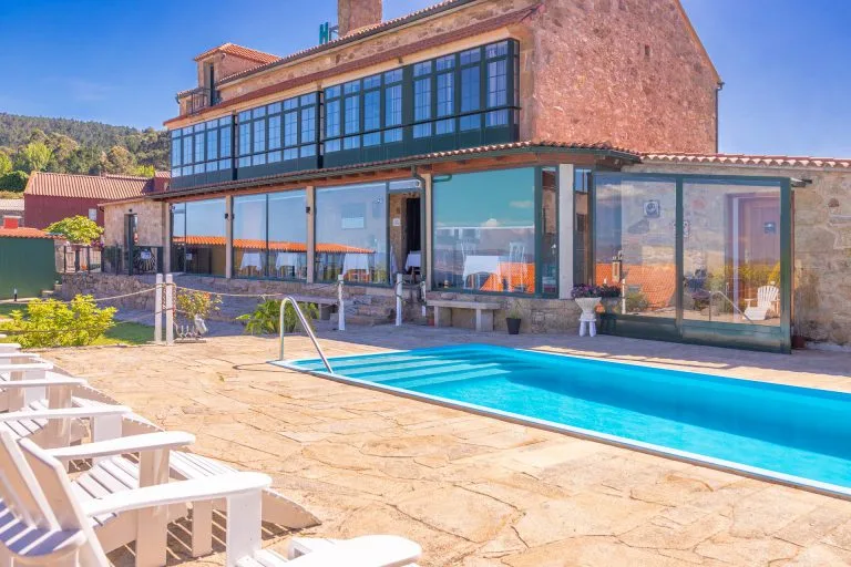 Espacio representativo del hotel: Una piscina exterior está junto a un edificio con fachada acristalada y asientos en el patio.