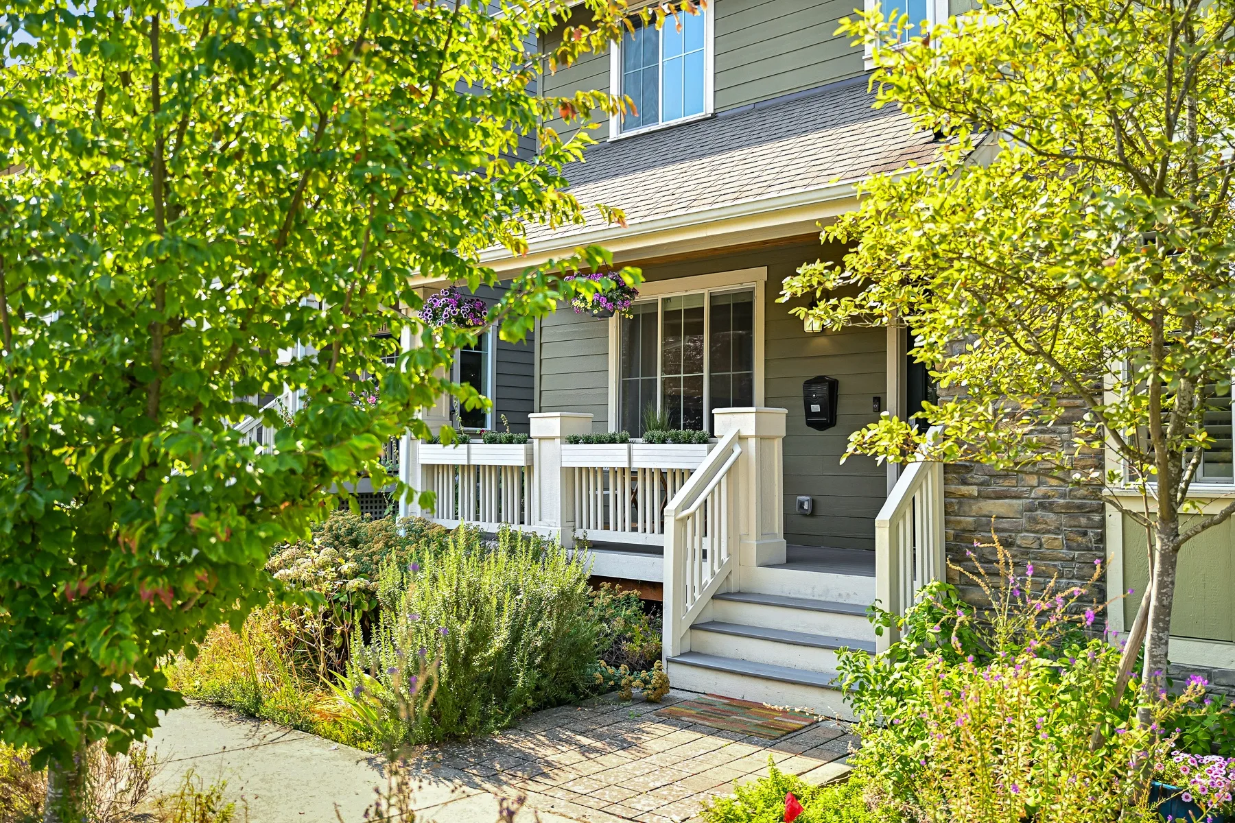 A house entrance with a small porch, white railings, and steps.