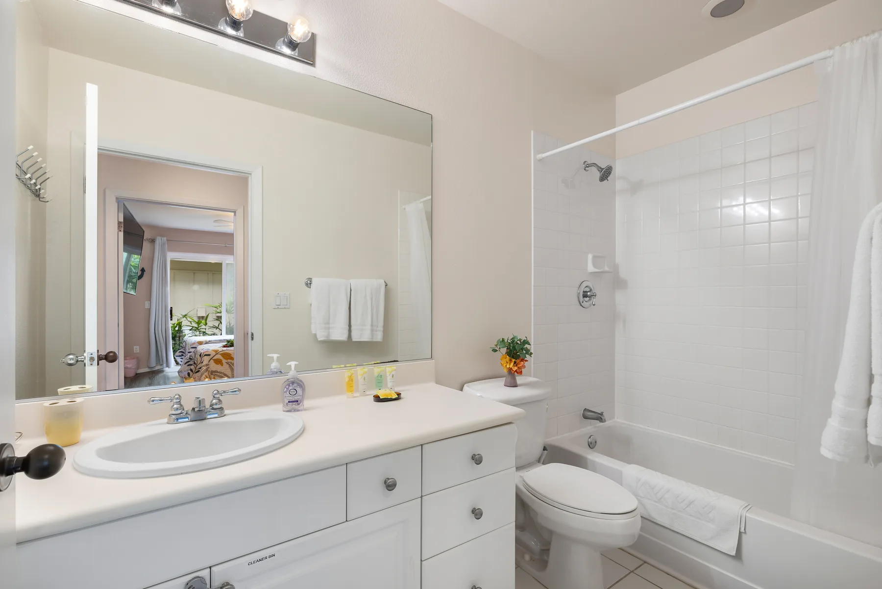 Un baño luminoso con lavabo, espejo, inodoro y bañera.