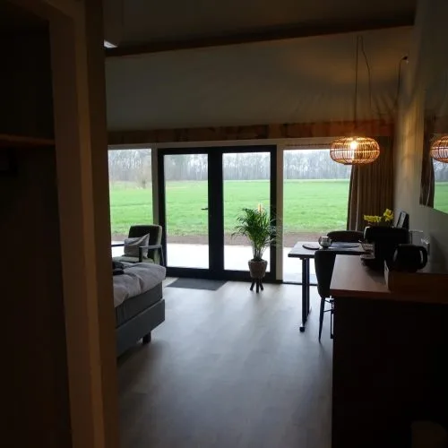 Espacio representativo del hotel: Una luminosa sala de estar da a un césped verde a través de grandes puertas de vidrio.