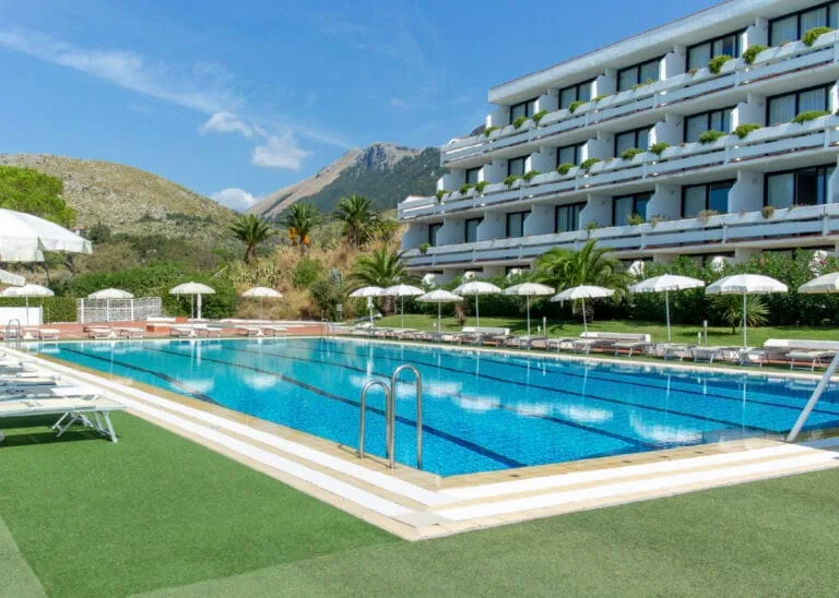 Espacio representativo del hotel: Una piscina al aire libre junto a un edificio hotelero y varias sombrillas.
