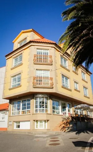 Espacio representativo del hotel: Edificio amarillo claro de varias plantas con balcones y una palmera.
