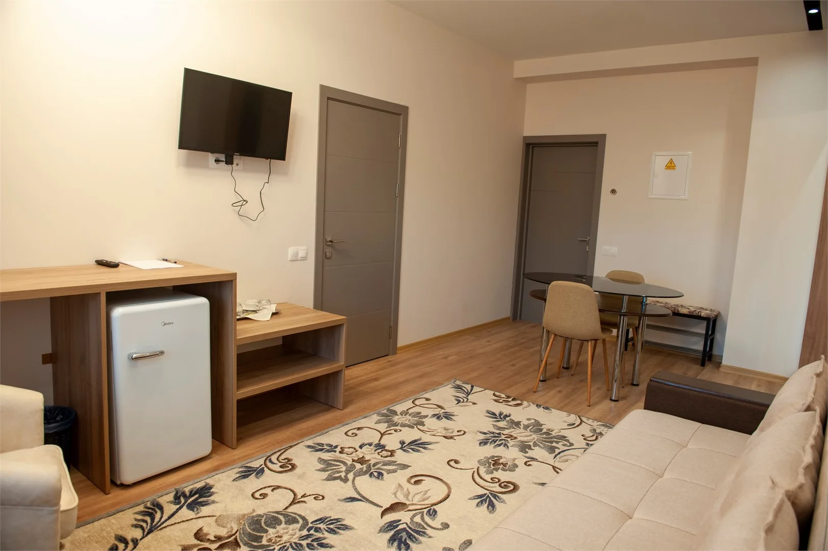 Espacio representativo del hotel: Una habitación amueblada con sofá, televisor y una pequeña mesa de comedor.