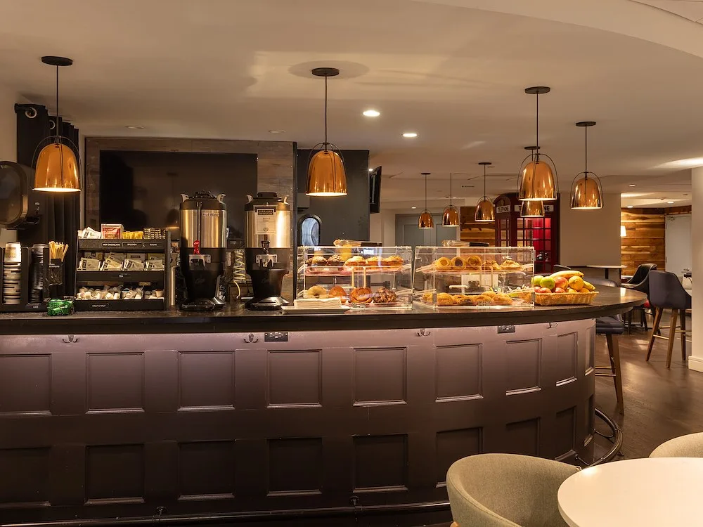 Representative hotel space: A café counter displays pastries and drinks beneath hanging lights.