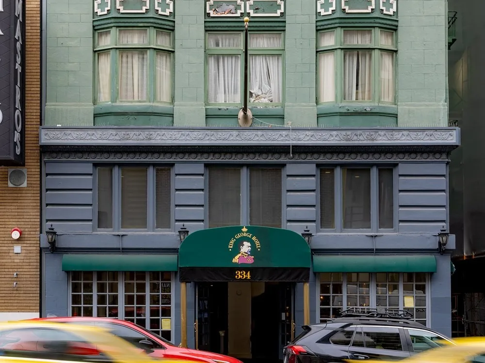 Representative hotel space: A city hotel facade has green upper windows and a dark entrance awning.