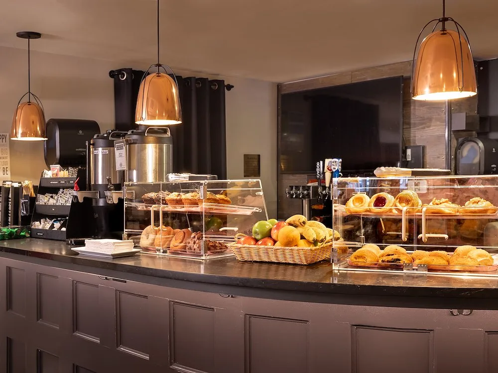 Representative hotel space: A hotel breakfast counter displays pastries and fruit beneath pendant lights.