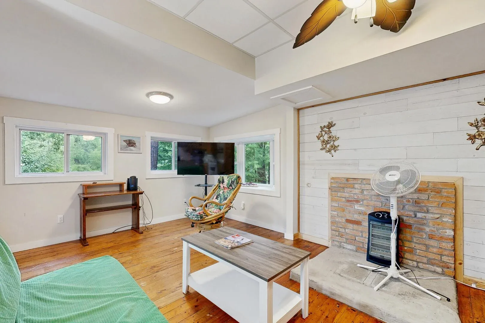 A living room with a television, seating, and a brick fireplace.