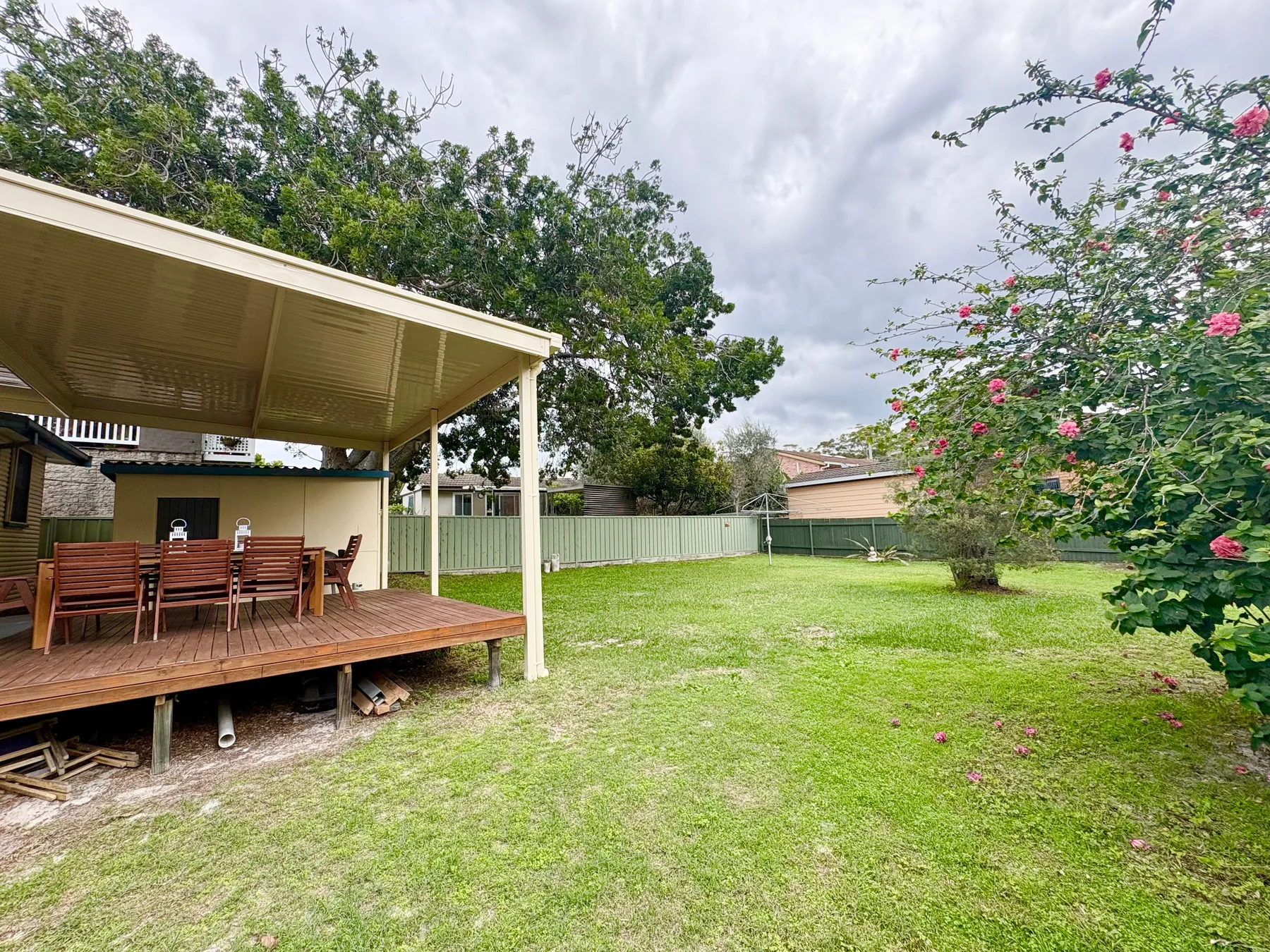 A grassy backyard with a covered wooden patio and outdoor seating.