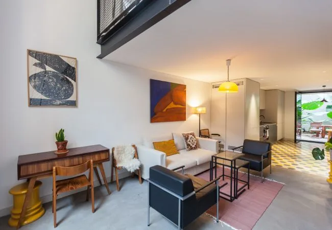 Una sala de estar moderna con asientos alrededor de una mesa de centro y un escritorio junto a la pared.