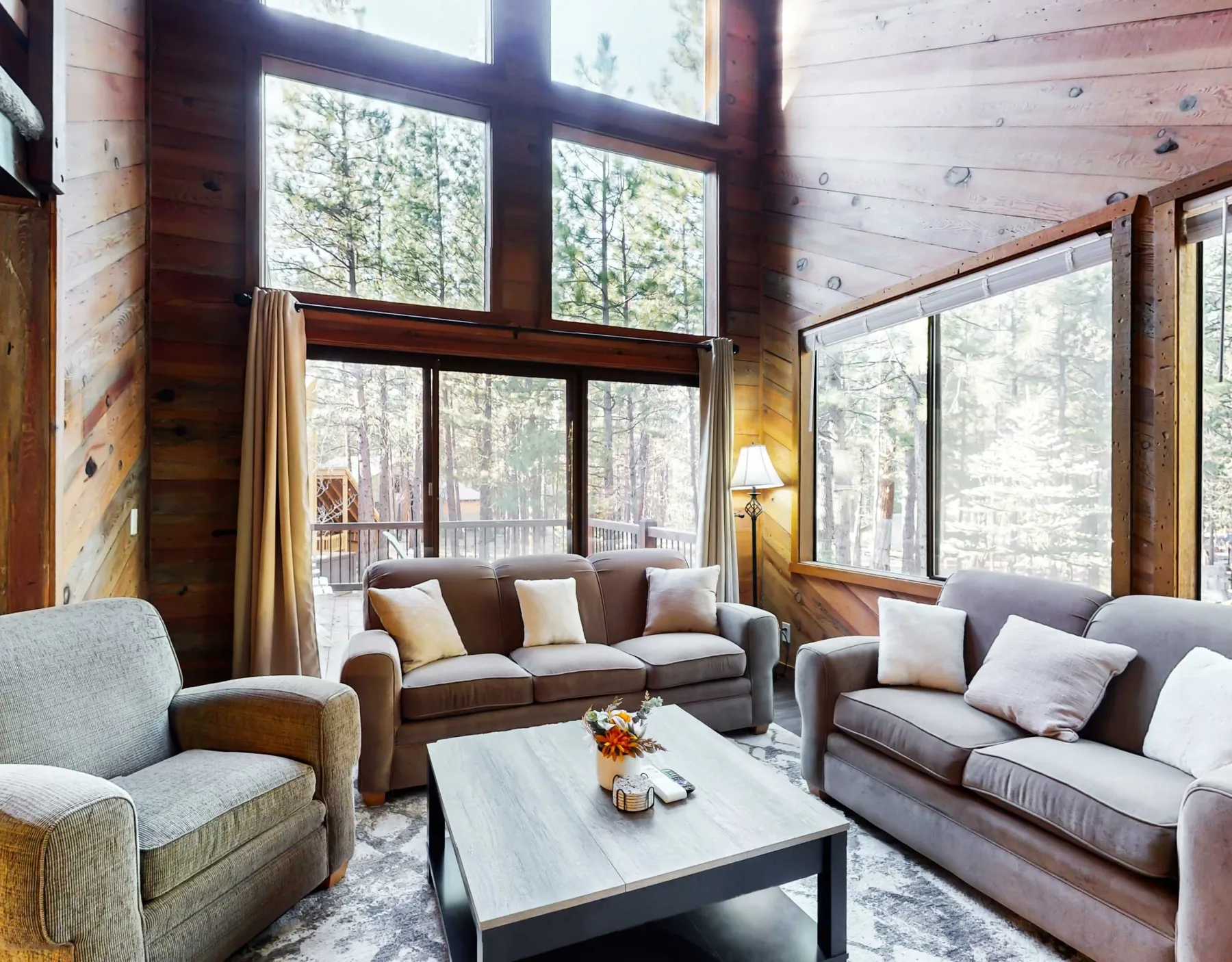 Una sala luminosa con asientos y grandes ventanas con vistas a los árboles.