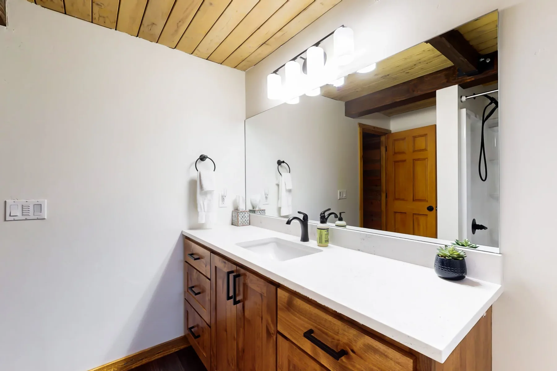 Un lavabo de baño con un espejo amplio y muebles de madera.