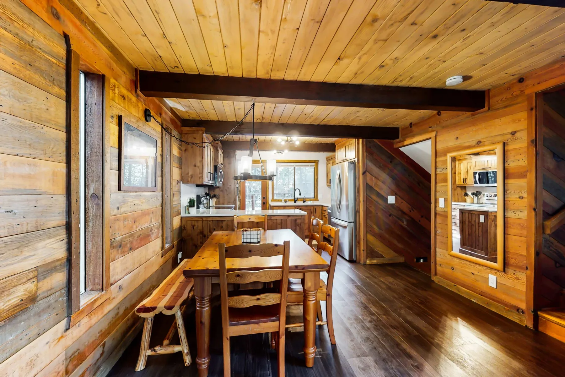 Comedor revestido de madera con una mesa y asientos junto a la cocina.