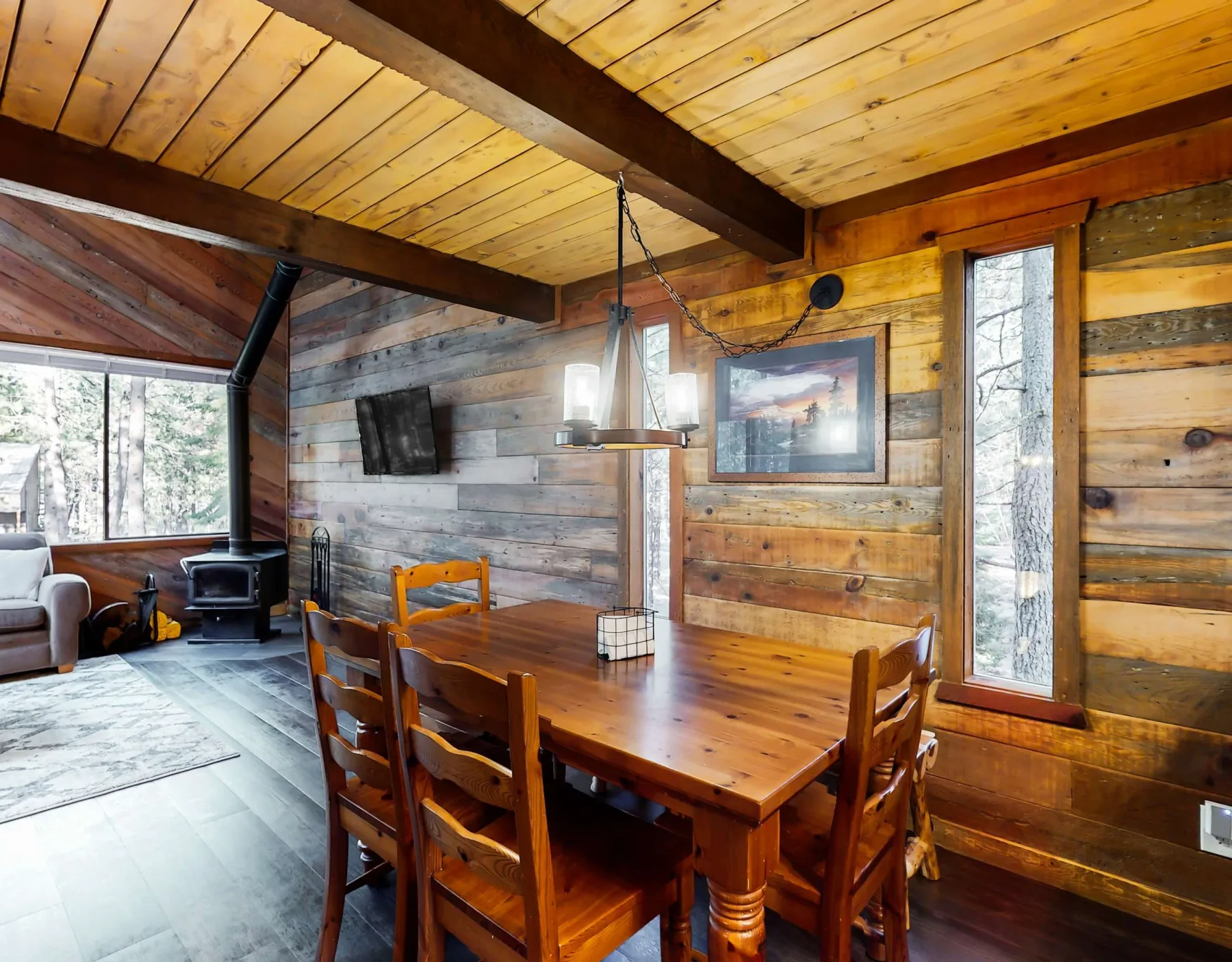 Un comedor rústico con una mesa de madera y grandes ventanas.