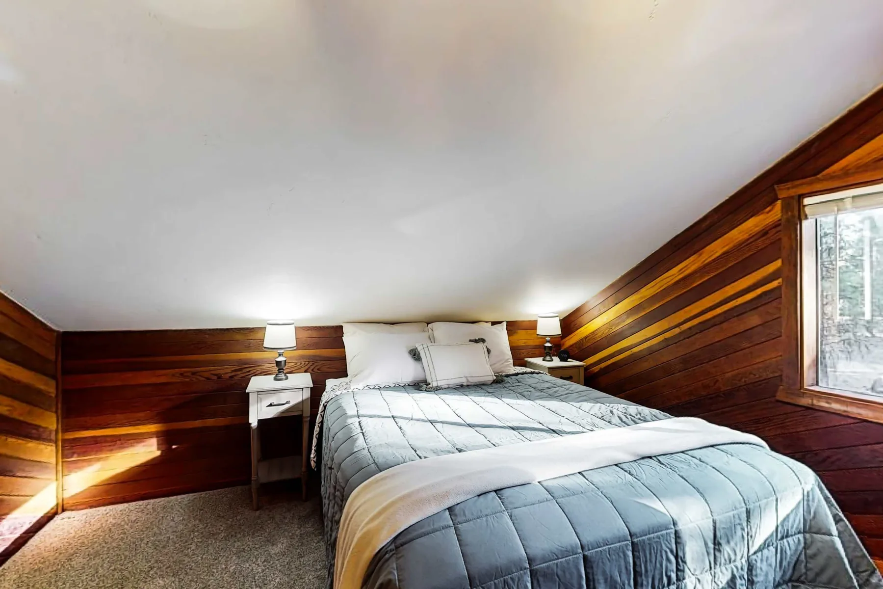 Un dormitorio con una cama bien tendida y paredes revestidas de madera.