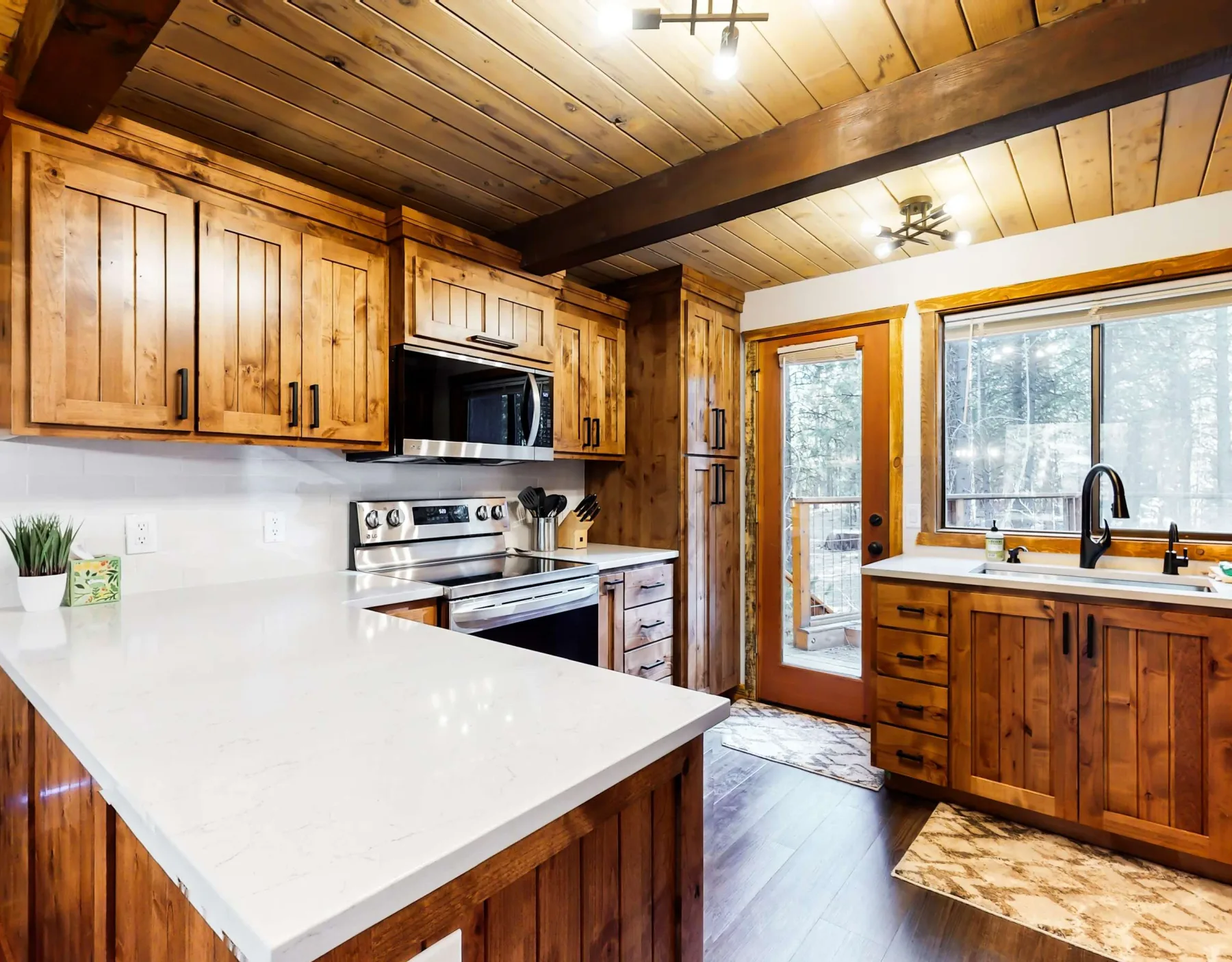 Una cocina revestida de madera, con una isla amplia y un fregadero bajo la ventana.