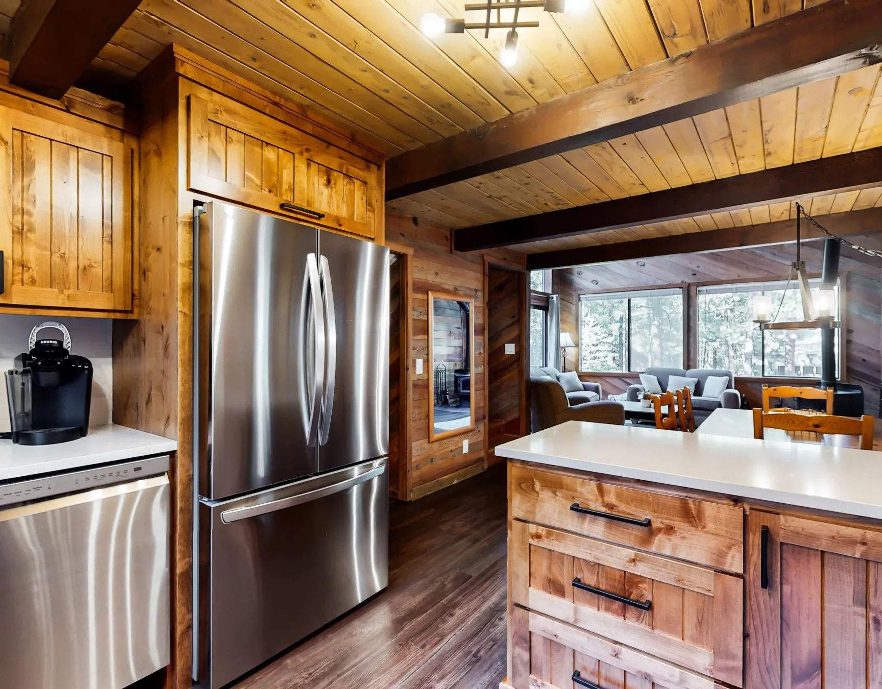 Una cocina revestida de madera se abre a un comedor y sala de estar con ventanales.
