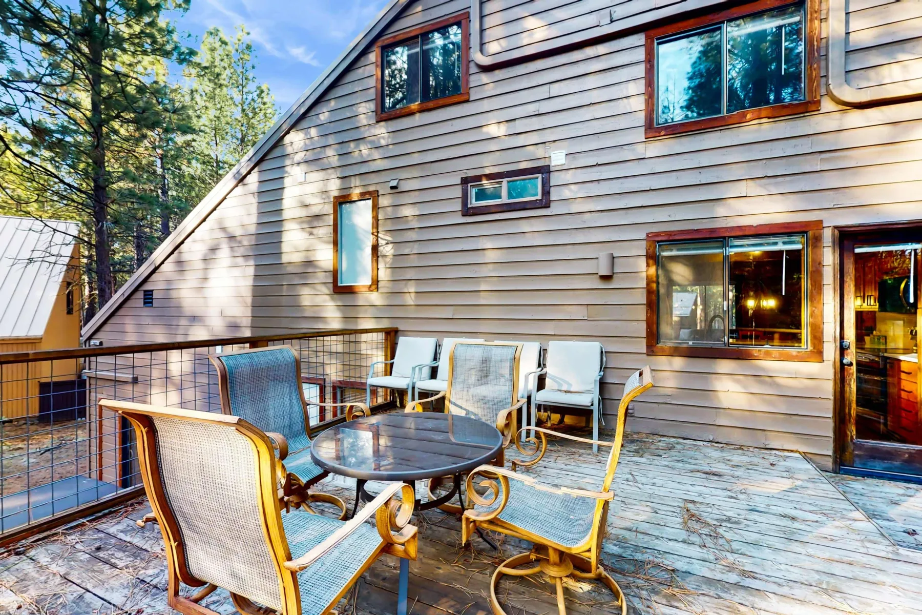 Una terraza exterior con asientos y una mesa junto a una casa revestida de madera.