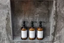 A recessed shelf holds three bottles against a textured gray wall.