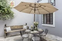 Shared amenity: An outdoor seating area with a table and umbrella beside a white wall.