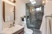 A bathroom with a glass shower, sink, and toilet.