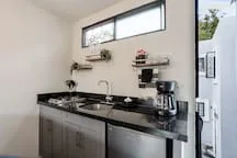 A modern kitchen with dark countertops, cabinets, and a high horizontal window.