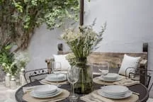 Shared amenity: A dining table set with plates and glasses sits in a leafy outdoor courtyard.