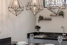 A dining area with hanging geometric light fixtures above a table.