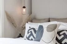 A bedroom scene with patterned pillows on a bed beside a hanging light.