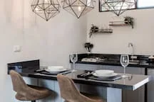 A dining area with a set table and geometric pendant lights overhead.