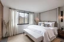A bright bedroom with a bed and a large window.
