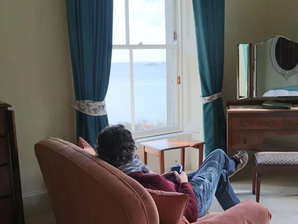 Espacio representativo del hotel: Una persona descansa en una sala junto a una ventana con vistas al agua.