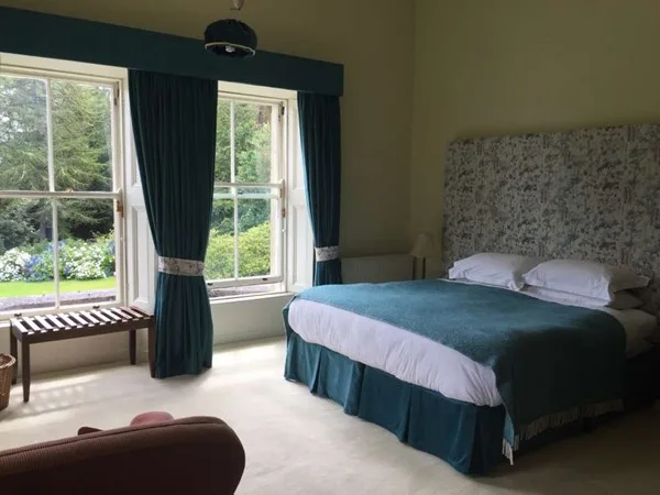 Espacio representativo del hotel: Un dormitorio con una cama doble junto a grandes ventanas con cortinas.