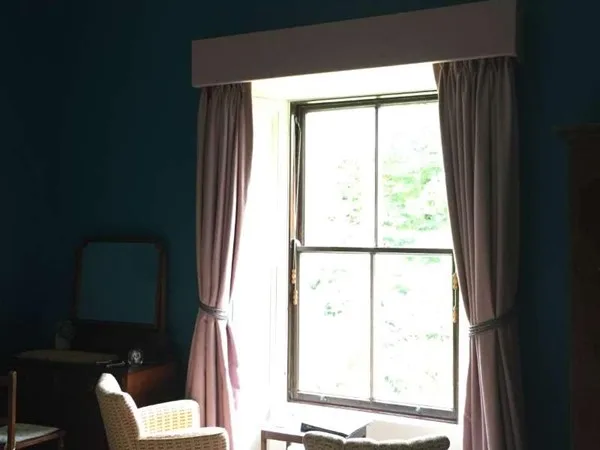 Espacio representativo del hotel: Una ventana del dormitorio con cortinas recogidas deja entrar la luz del día.