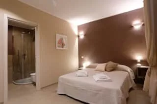 Espacio representativo del hotel: Un dormitorio con una cama bien tendida y un cuadro en la pared.