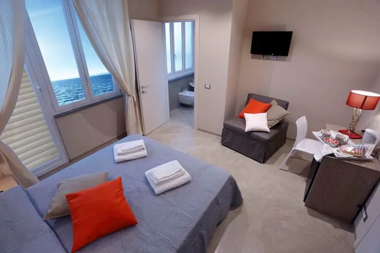 Espacio representativo del hotel: Un dormitorio con una cama, una ventana con vistas al mar y una pequeña zona de estar.