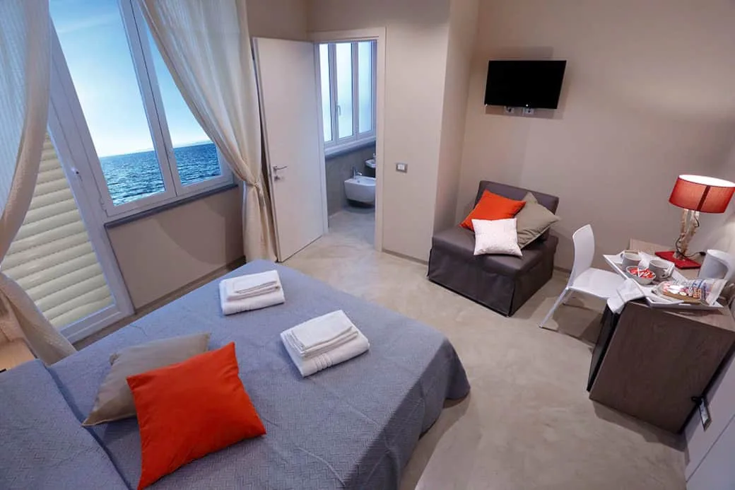 Espacio representativo del hotel: Un dormitorio con una cama junto a una ventana con vistas al mar.