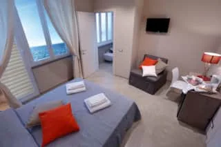 Espacio representativo del hotel: Un dormitorio de hotel con cama, asientos y una ventana con vista al agua.