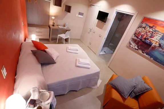 Espacio representativo del hotel: Un dormitorio con una cama tendida, un escritorio y un televisor en la pared.