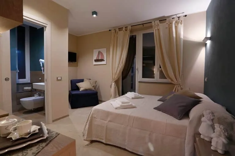 Espacio representativo del hotel: Un dormitorio con una cama bien tendida y una ventana con cortinas.