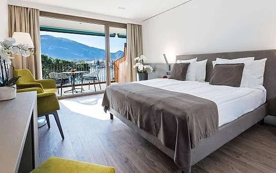 Espacio representativo del hotel: Un dormitorio luminoso con una cama grande y puertas corredizas de vidrio que dan a un balcón.