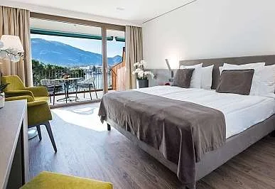 Espacio representativo del hotel: Un dormitorio luminoso con una cama grande y puertas corredizas de vidrio que dan a un balcón.