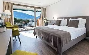 Espacio representativo del hotel: Un dormitorio con una cama grande junto a puertas de vidrio que dan a un balcón.
