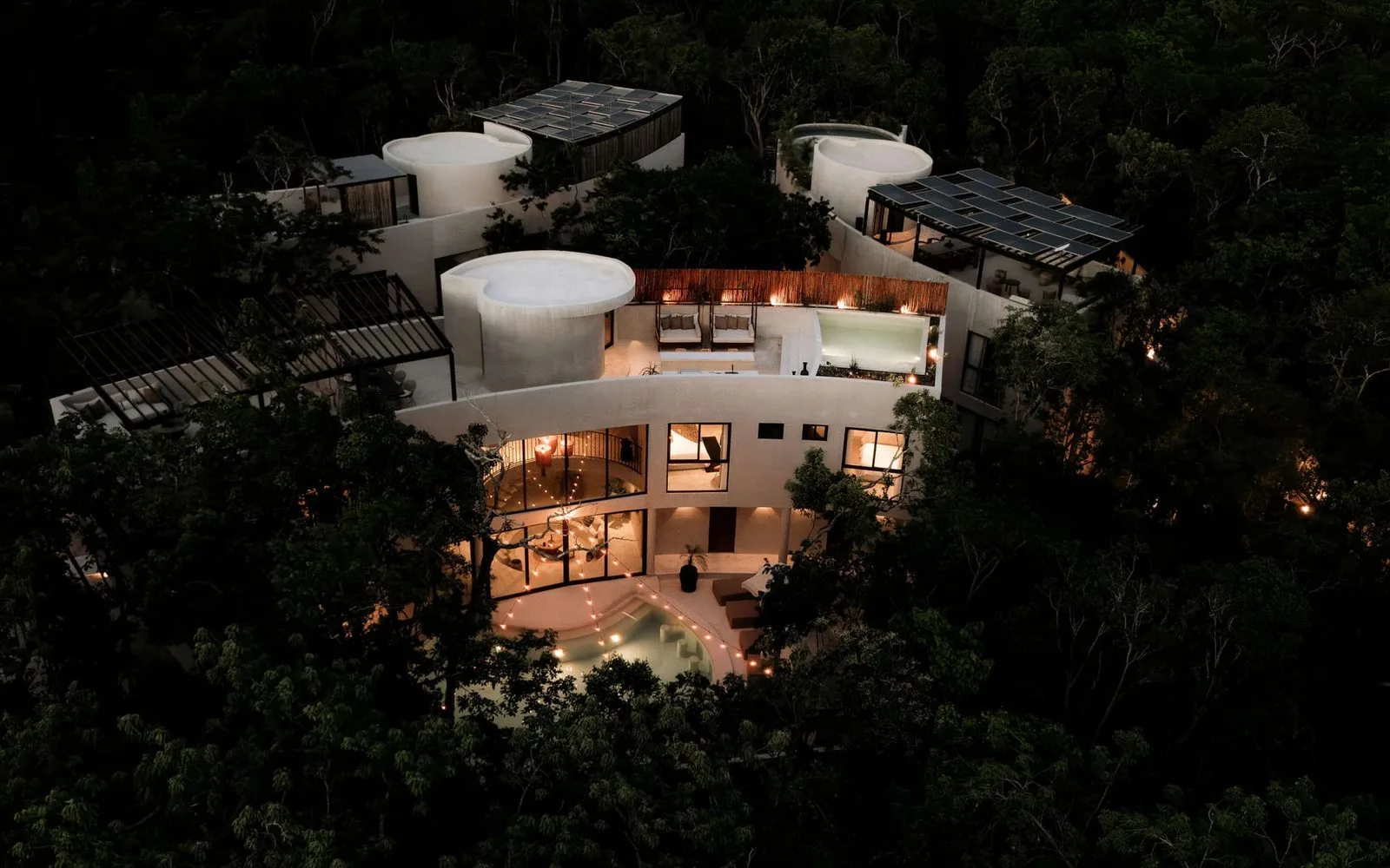Un edificio moderno iluminado entre árboles frondosos de noche.