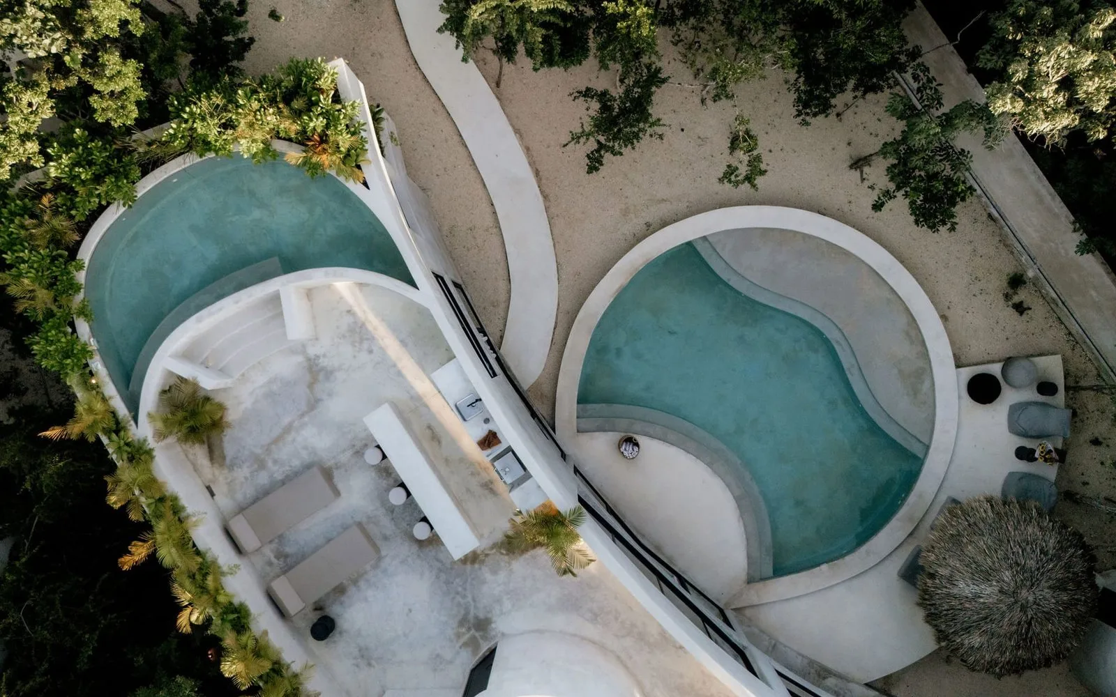 Vista aérea de dos piscinas curvas rodeadas de vegetación.