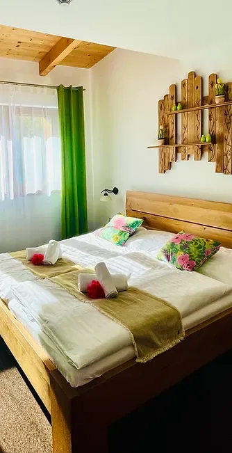 Representative hotel space: A bedroom with a wooden bed dressed in white linens and colorful pillows.