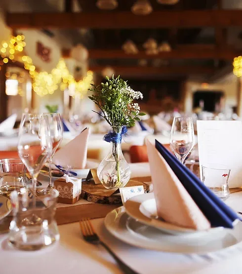 Representative hotel space: A dining room table is set with folded napkins, glassware, and flowers.