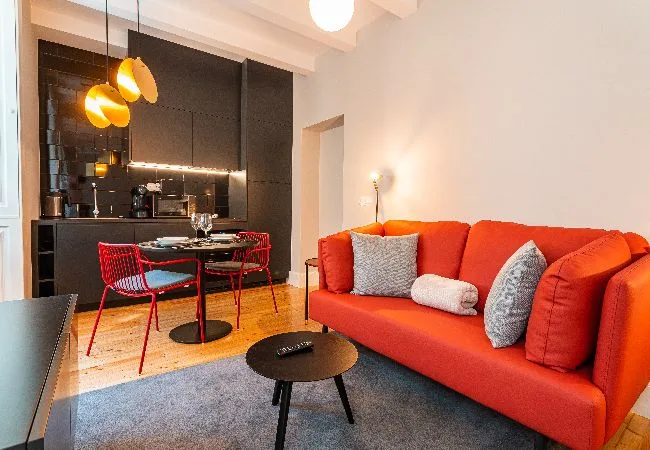 A bright living and dining area with a red sofa and a small dining table.