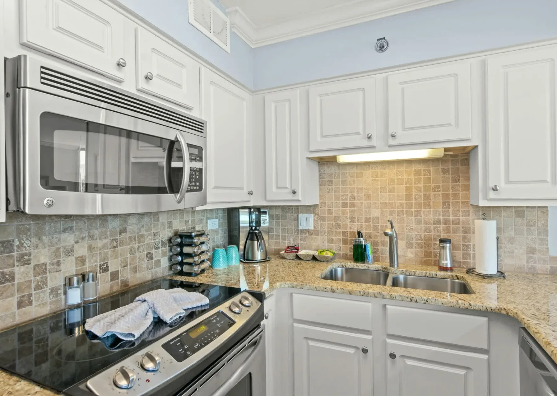 Una cocina luminosa con gabinetes blancos, un salpicadero de azulejos y una encimera.